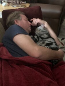 Remy, an American Shorthair cat sleeping with dad.